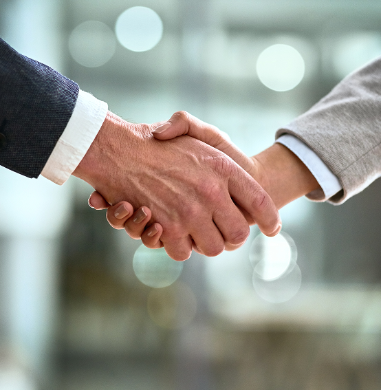 a close-up of two people in formal attire shaking hands, suggesting a business agreement