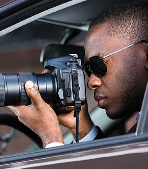 A professional detective holding a camera to capture someone