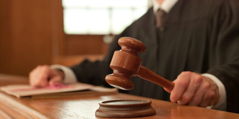 This image depicts a judge in a courtroom setting, holding a wooden gavel.