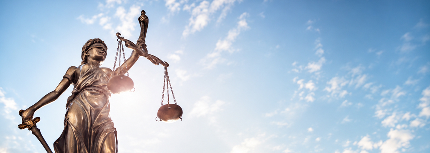 This image depicts a bronze statue of Lady Justice against a blue sky, commonly used as a conceptual stock photo for legal topics.