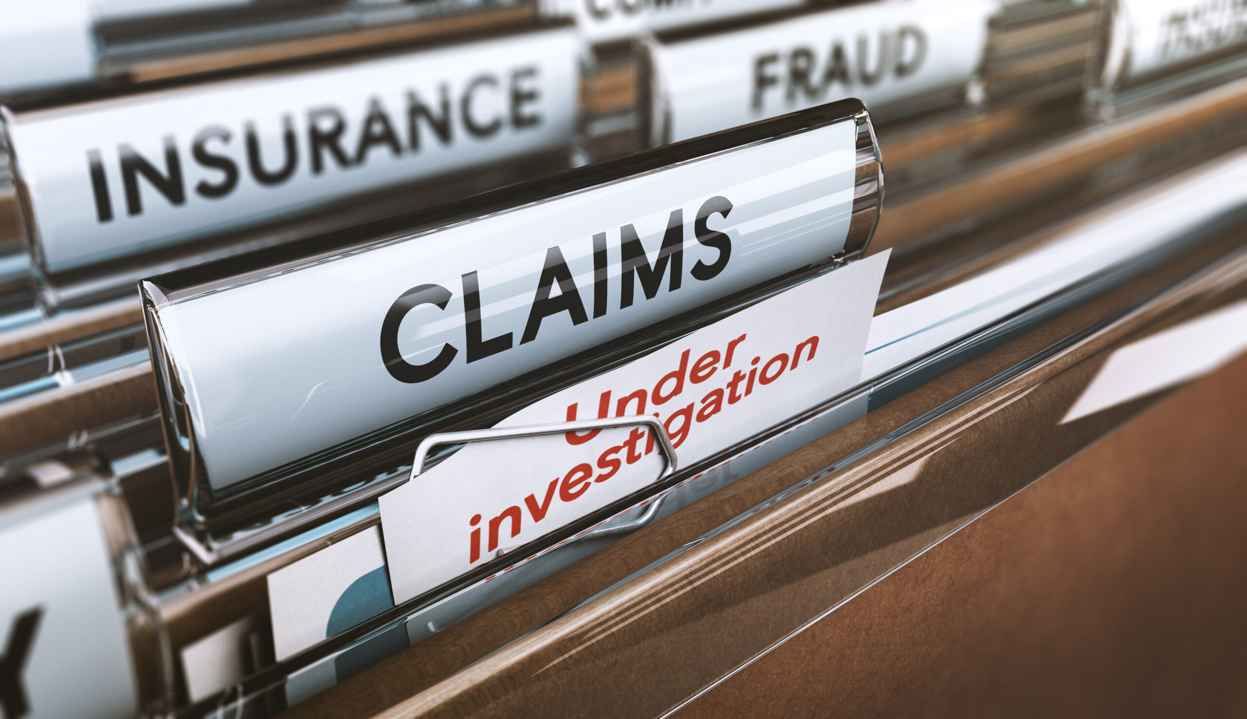 A file folder labeled "CLAIMS" labeled as "Under Investigation," a scenario that occurs during the evaluation of potentially fraudulent or complex insurance claims.
